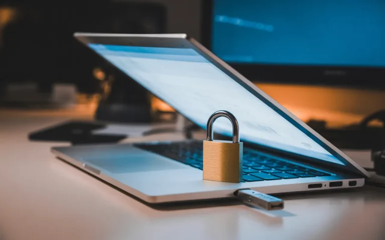 Comment éviter les piratages sur WordPress : gros plan d’un ordinateur portable en aluminium, cadenas sur le clavier et clé de sécurité USB branchée, écran d’administration flou, lumière nocturne bleutée.